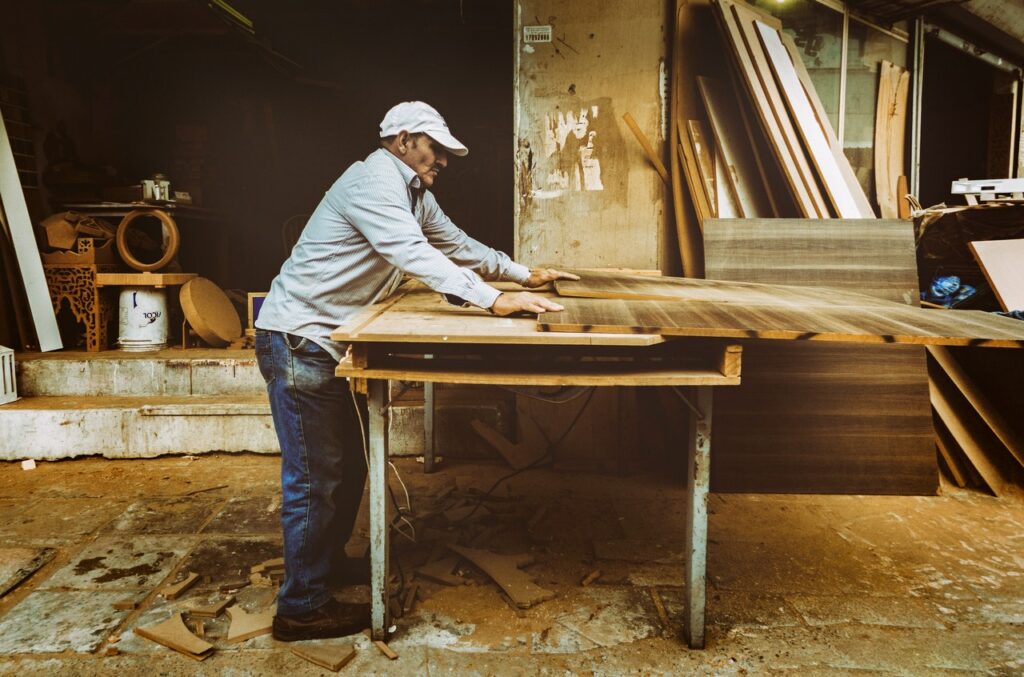 Mann bearbeitet Holz mit Tischkreissäge Nachhaltige Produktion ökologischer Möbel