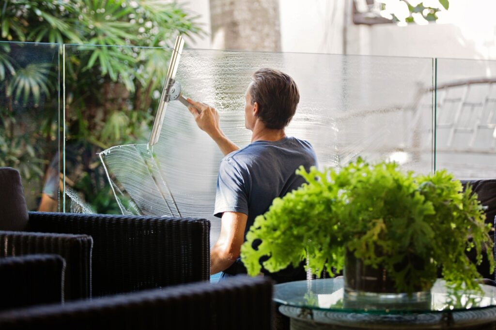 Mann putzt Fenster grün Nachhaltige Reinigung – mehr Umweltbewusstsein im Haushalt